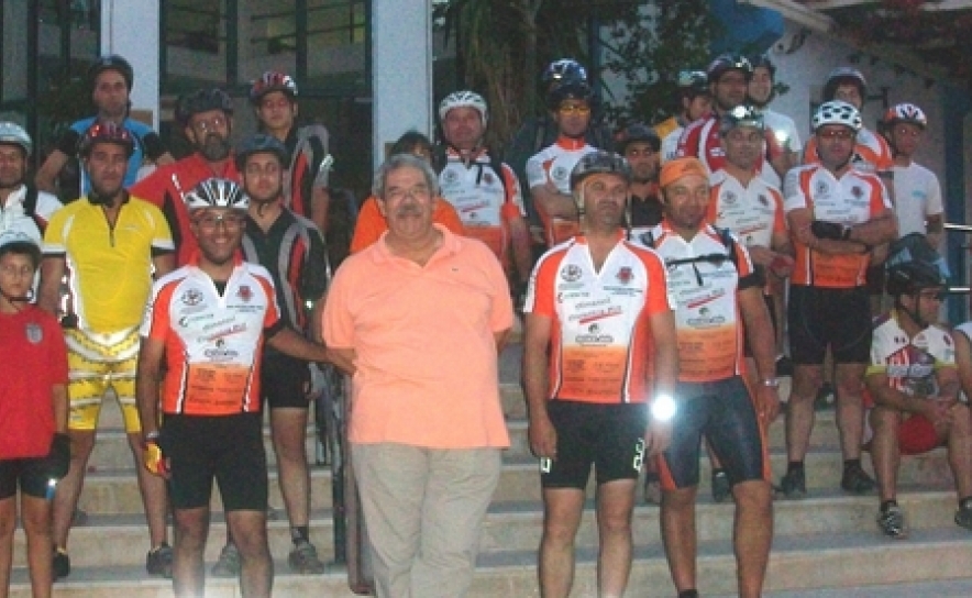 Hermes Alberto ao centro, tendo como pano de fundo a ASCA, com voluntários das bicicletas, numa corrida solidária. 